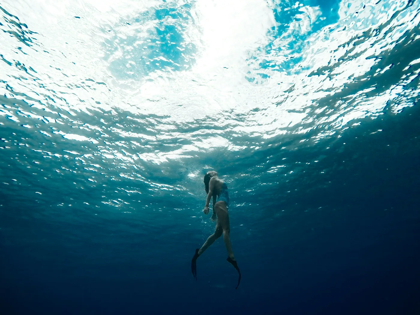 A scuba diver descending through clear blue water